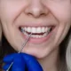 Dentysta wskazuje białą plamę na przednim zębie pacjentki podczas badania stomatologicznego.