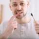 Mężczyzna wskazuje krwawiące dziąsło podczas szczotkowania zębów.
